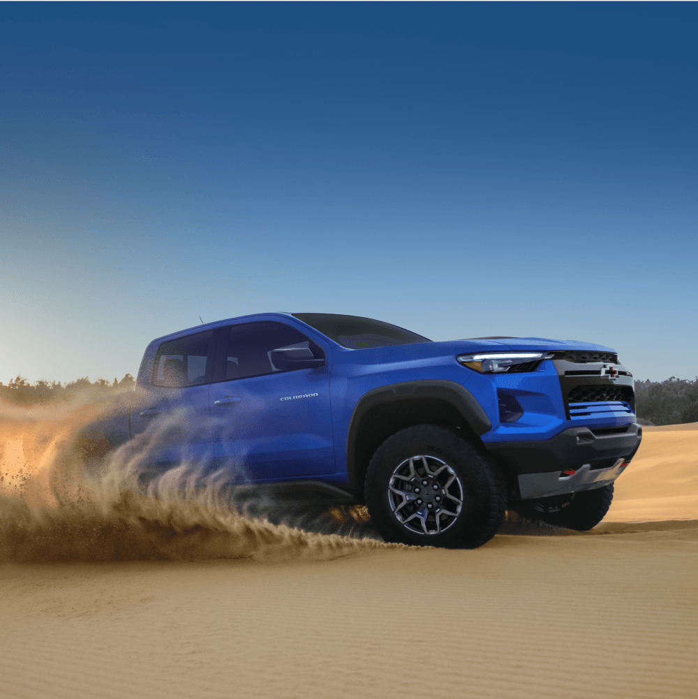 A blue Chevrolet Colorado ZR2 driving across sandy terrain